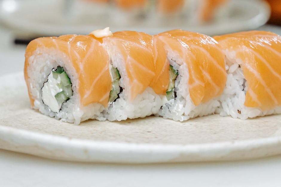 A plate of asparagus-sushi, showcasing fresh asparagus arranged on top of rolls, with a dash of soy sauce for dipping.
