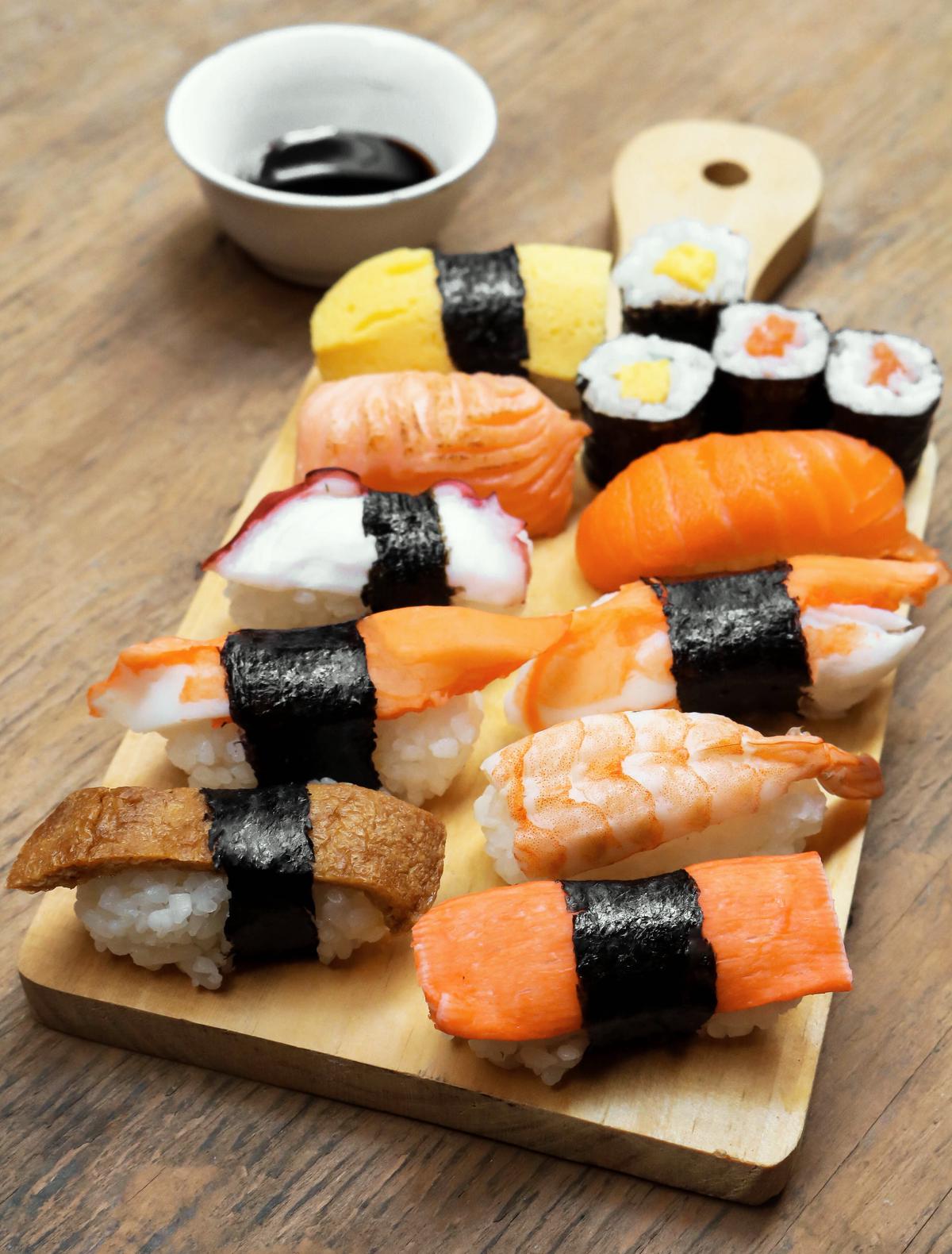A picture of deliciously prepared sushi on a traditional wooden plate.