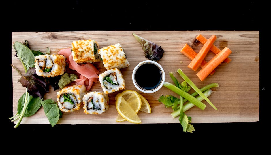 Person making sushi surrounded by fresh ingredients