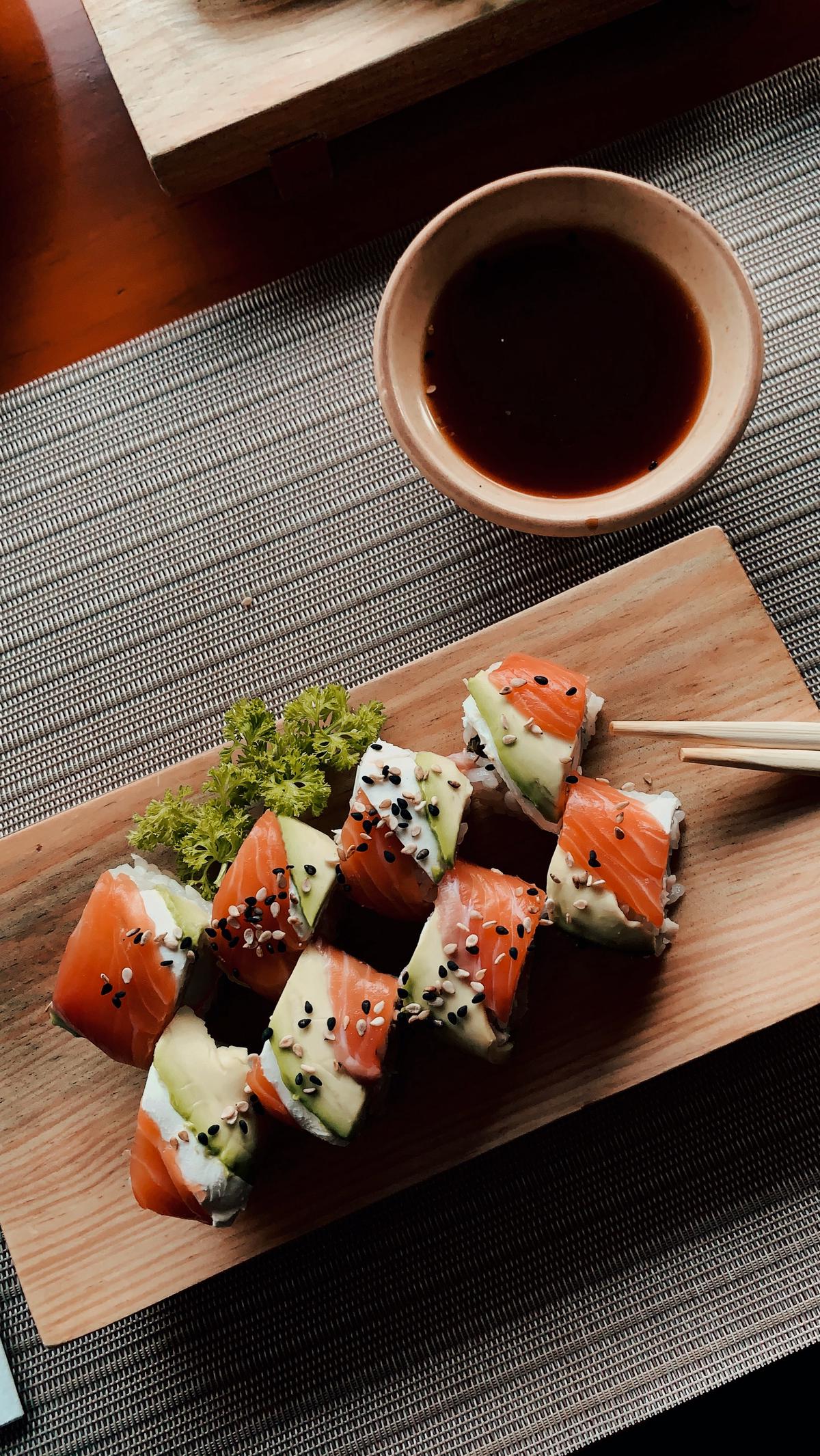 Un elegante arreglo de sushi en un plato blanco rodeado de palos de bambú