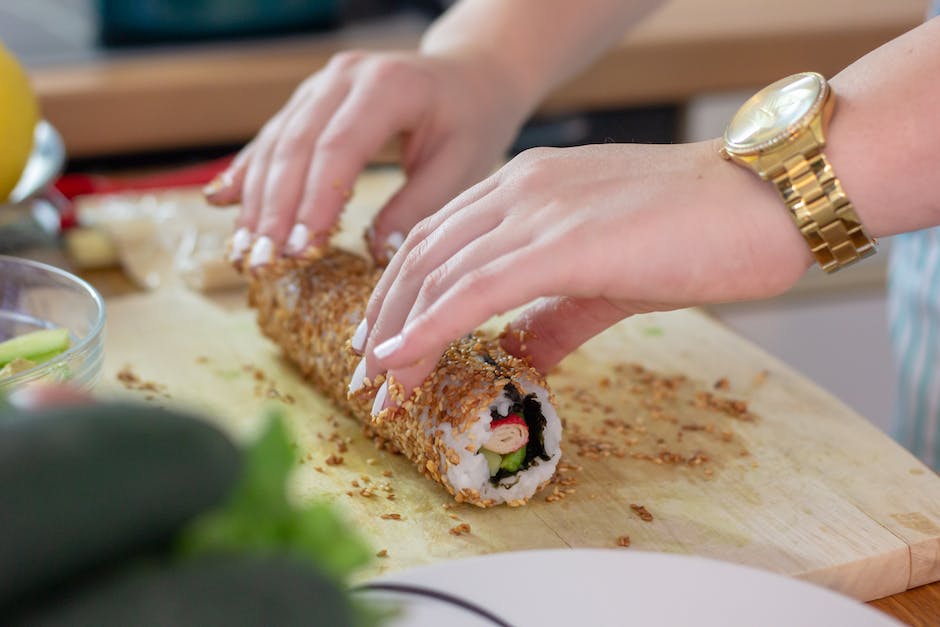 Una imagen en primer plano de manos enrollando sushi con ingredientes de colores vibrantes