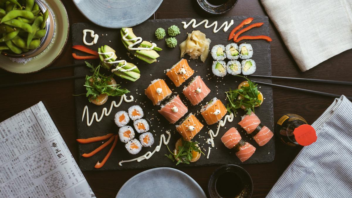 Una imagen que muestra el proceso de preparación del sushi, con varios ingredientes y herramientas.